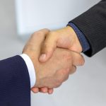 Close-up of two businessmen shaking hands, symbolizing agreement and partnership. Gros plan de deux hommes d'affaires se serrant la main, symbolisant l'accord et le partenariat.
