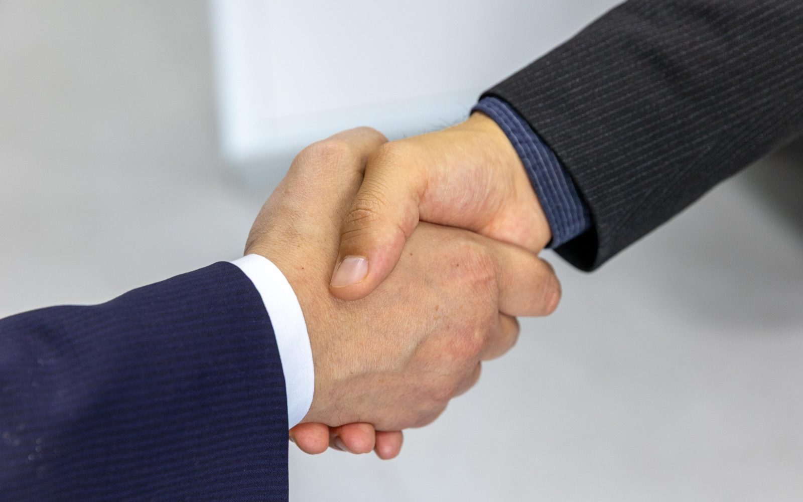 Close-up of two businessmen shaking hands, symbolizing agreement and partnership. Gros plan de deux hommes d'affaires se serrant la main, symbolisant l'accord et le partenariat.