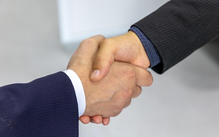 Close-up of two businessmen shaking hands, symbolizing agreement and partnership. Gros plan de deux hommes d'affaires se serrant la main, symbolisant l'accord et le partenariat.