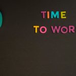 Minimalist image with a colorful clock and letters spelling 'Time to Work' on a black background. Image minimaliste avec une horloge colorée et des lettres orthographiant 'Time to Work' sur un fond noir.