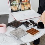 A close-up of interior design planning with material samples on a marble table. Un gros plan de la planification du design d'intérieur avec des échantillons de matériaux sur une table en marbre.