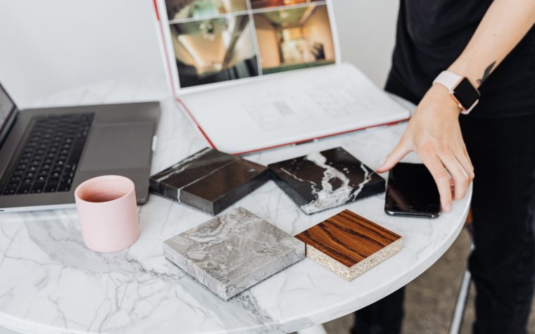 A close-up of interior design planning with material samples on a marble table. Un gros plan de la planification du design d'intérieur avec des échantillons de matériaux sur une table en marbre.