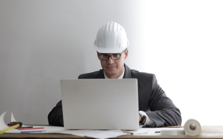 Ingénieur concentré travaillant sur plans et ordinateur portable