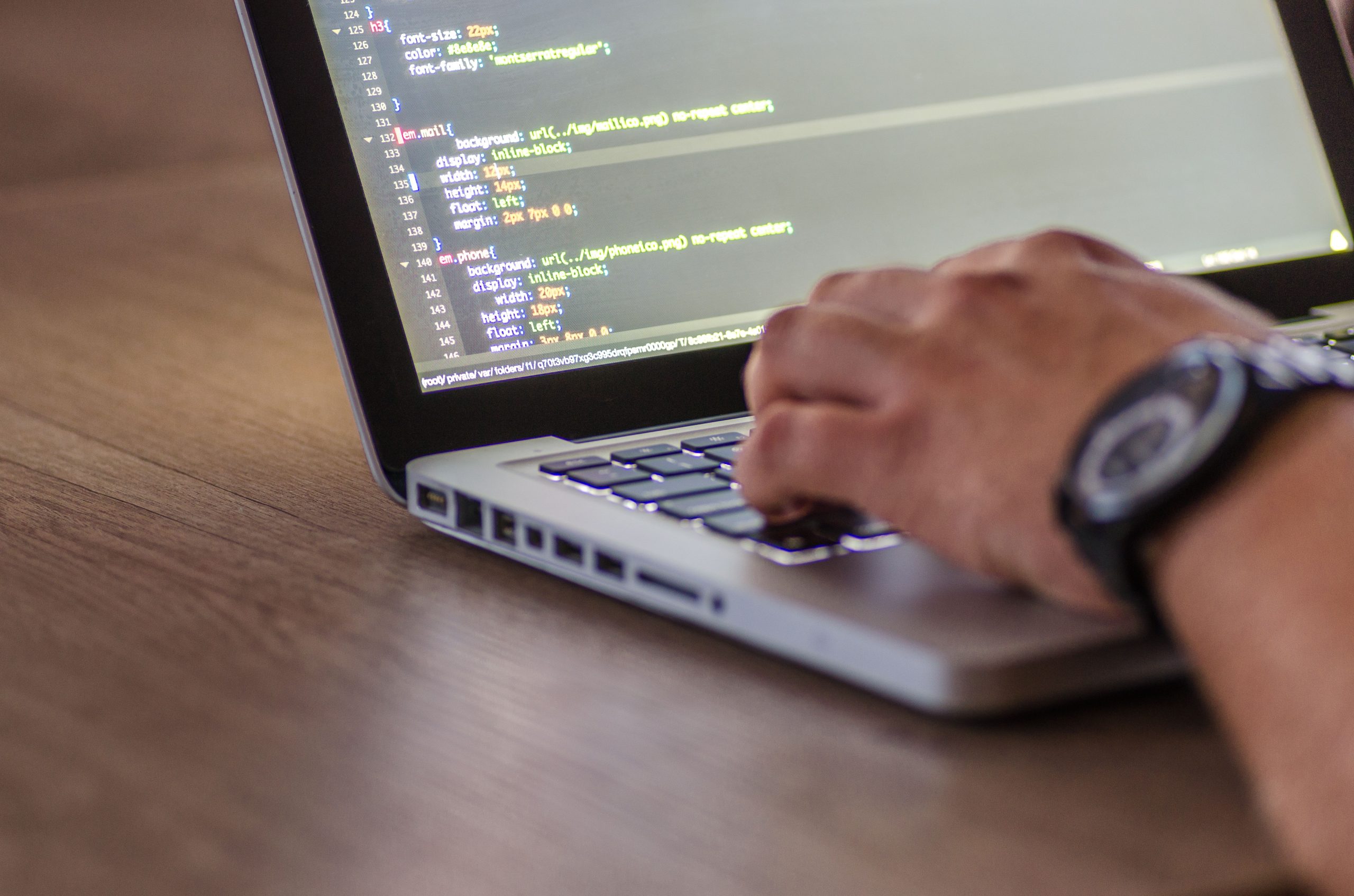 Gros plan mains développeur codant sur écran laptop