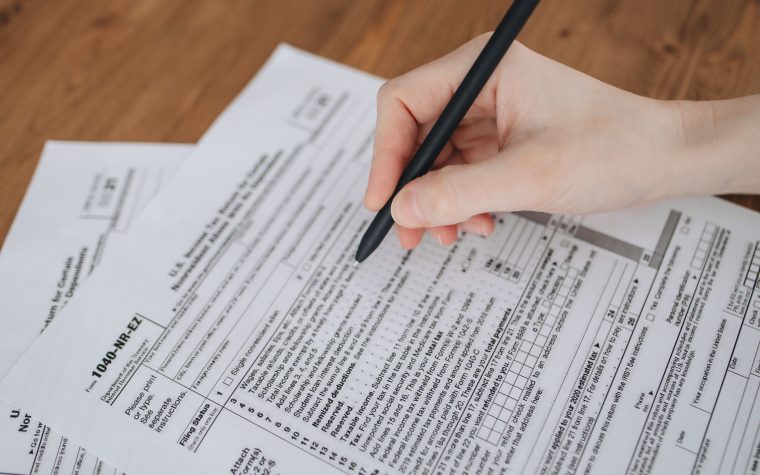 Main écrivant sur documents administratifs avec stylo noir