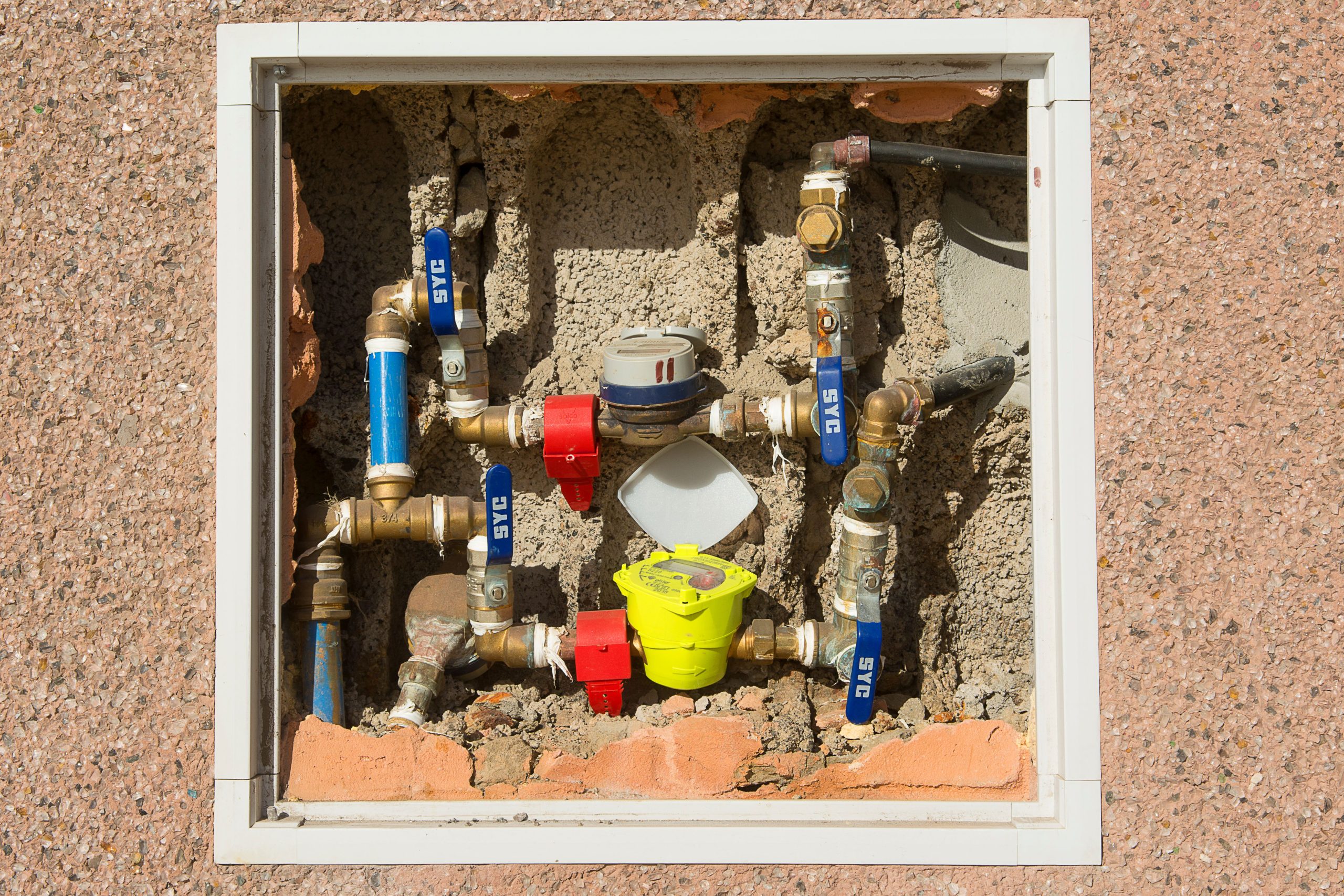 Compteur d'eau complexe encastré dans un mur béton