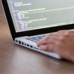 Développeur codant sur laptop avec code HTML affiché