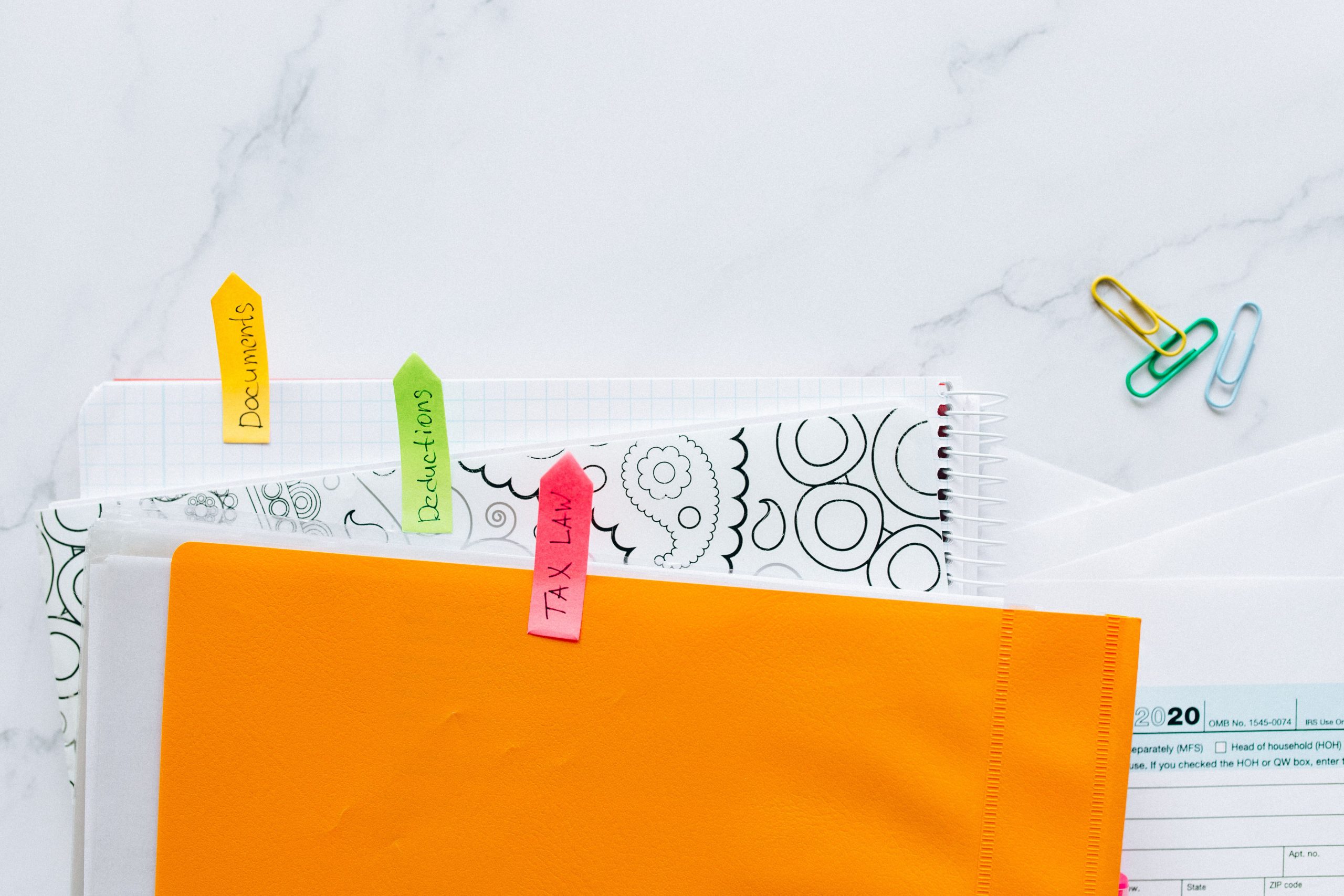 Documents organisés avec post-it colorés sur bureau marbre