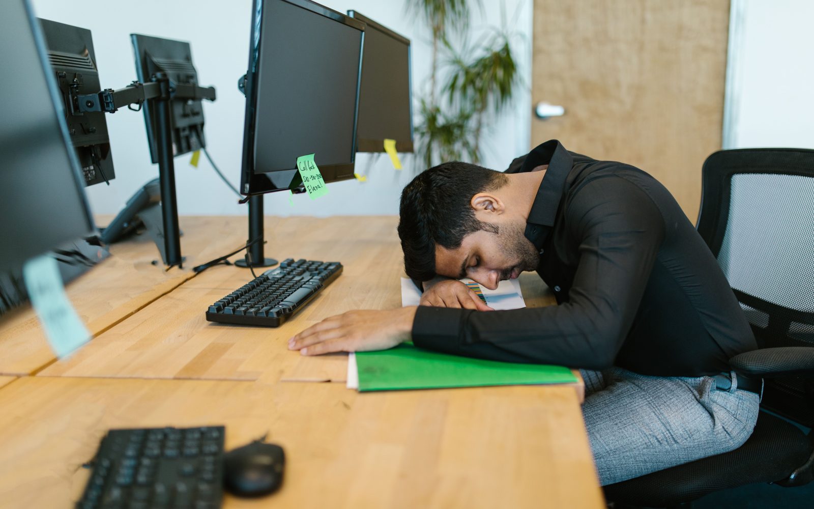 Employé épuisé reposant à son bureau entouré d'écrans