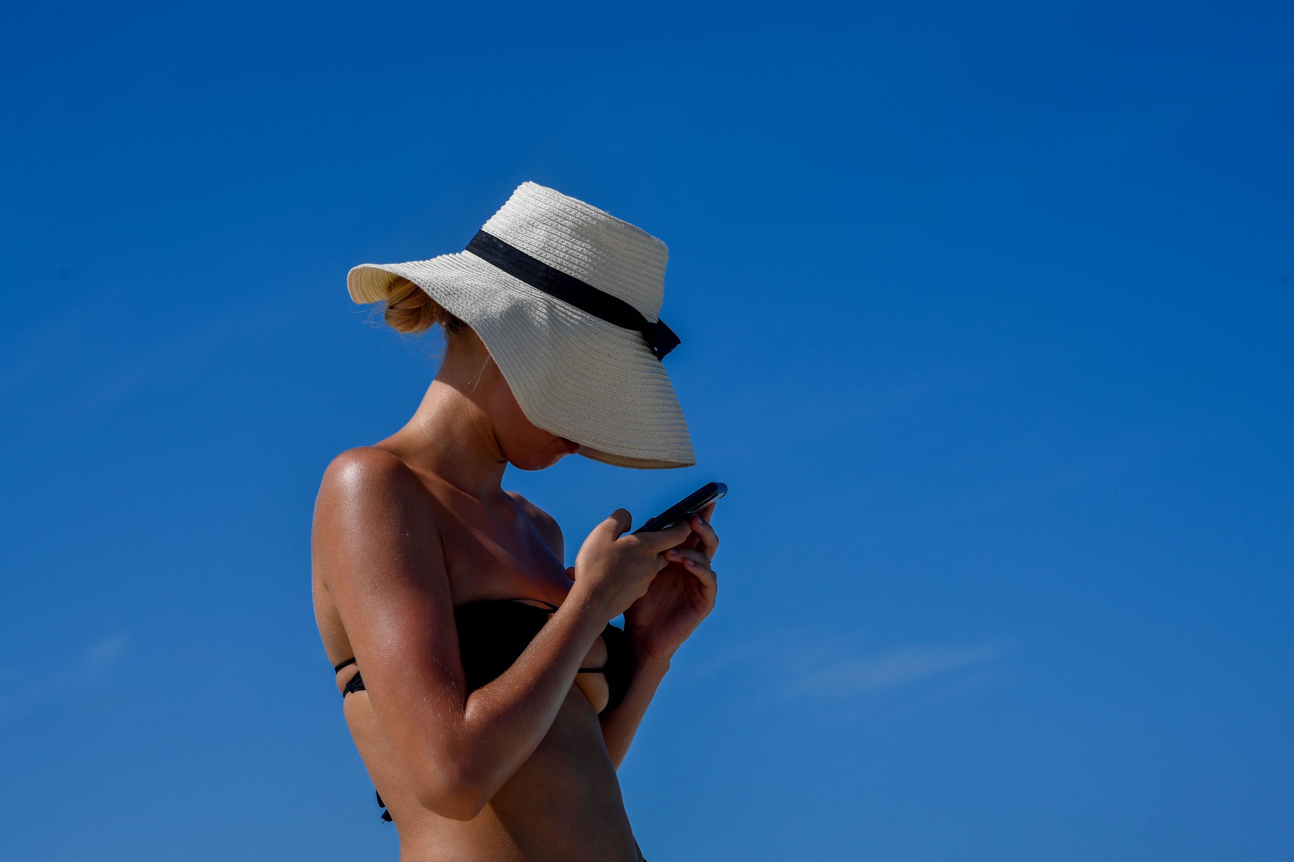 Femme utilisant téléphone à la plage sous soleil