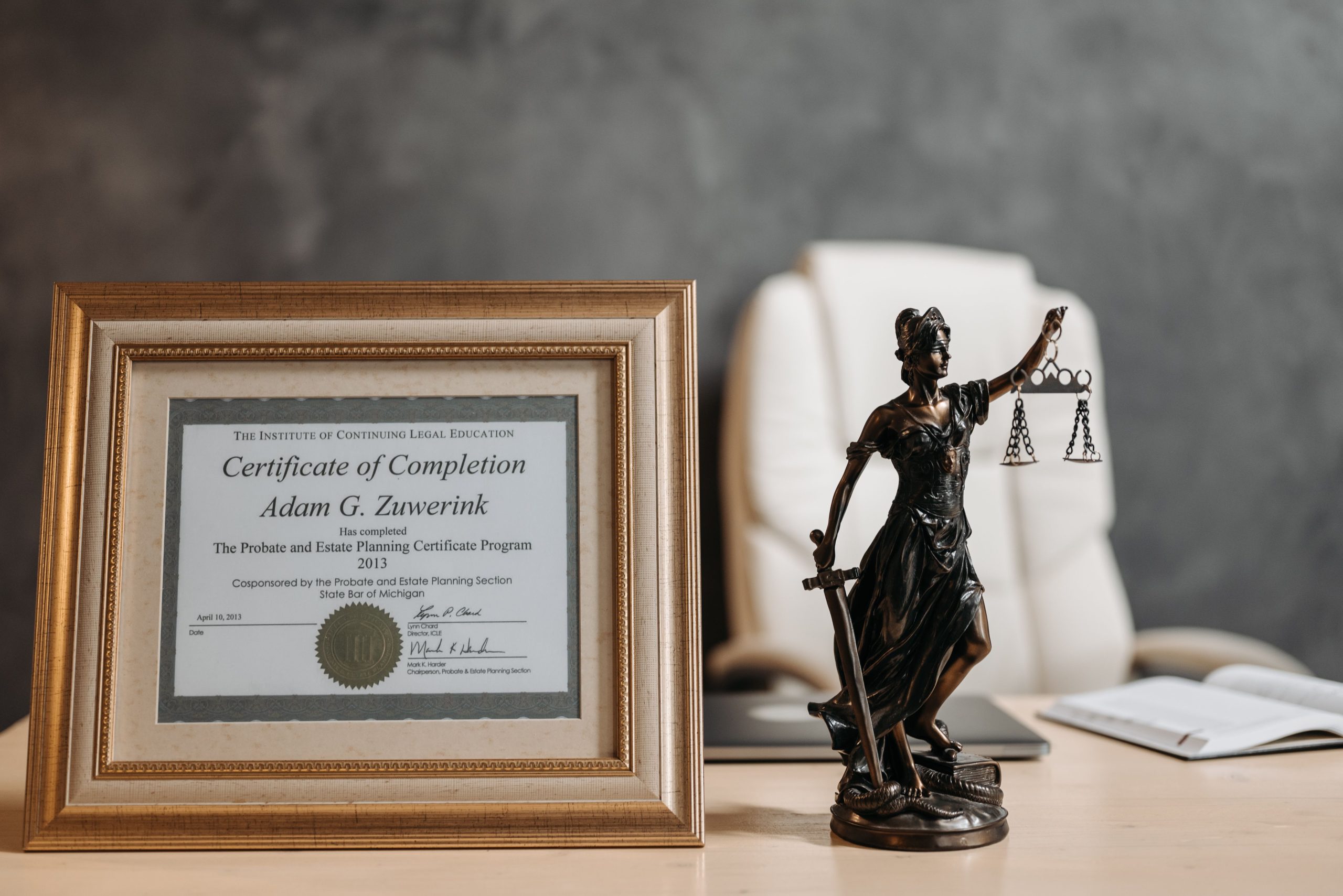 Certificat encadré et statue de la Justice sur bureau