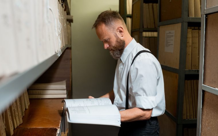 Homme consultant un grand registre en archive