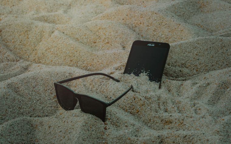 Smartphone et lunettes dans le sable de plage