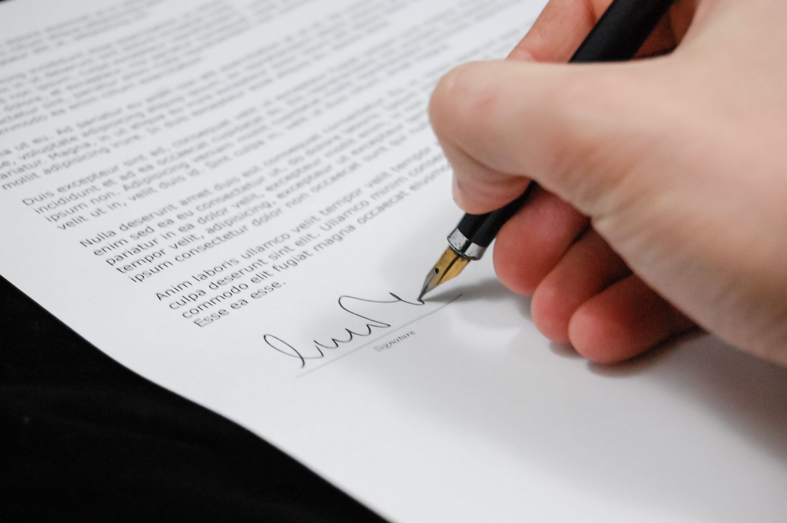 Main signant un document légal avec un stylo