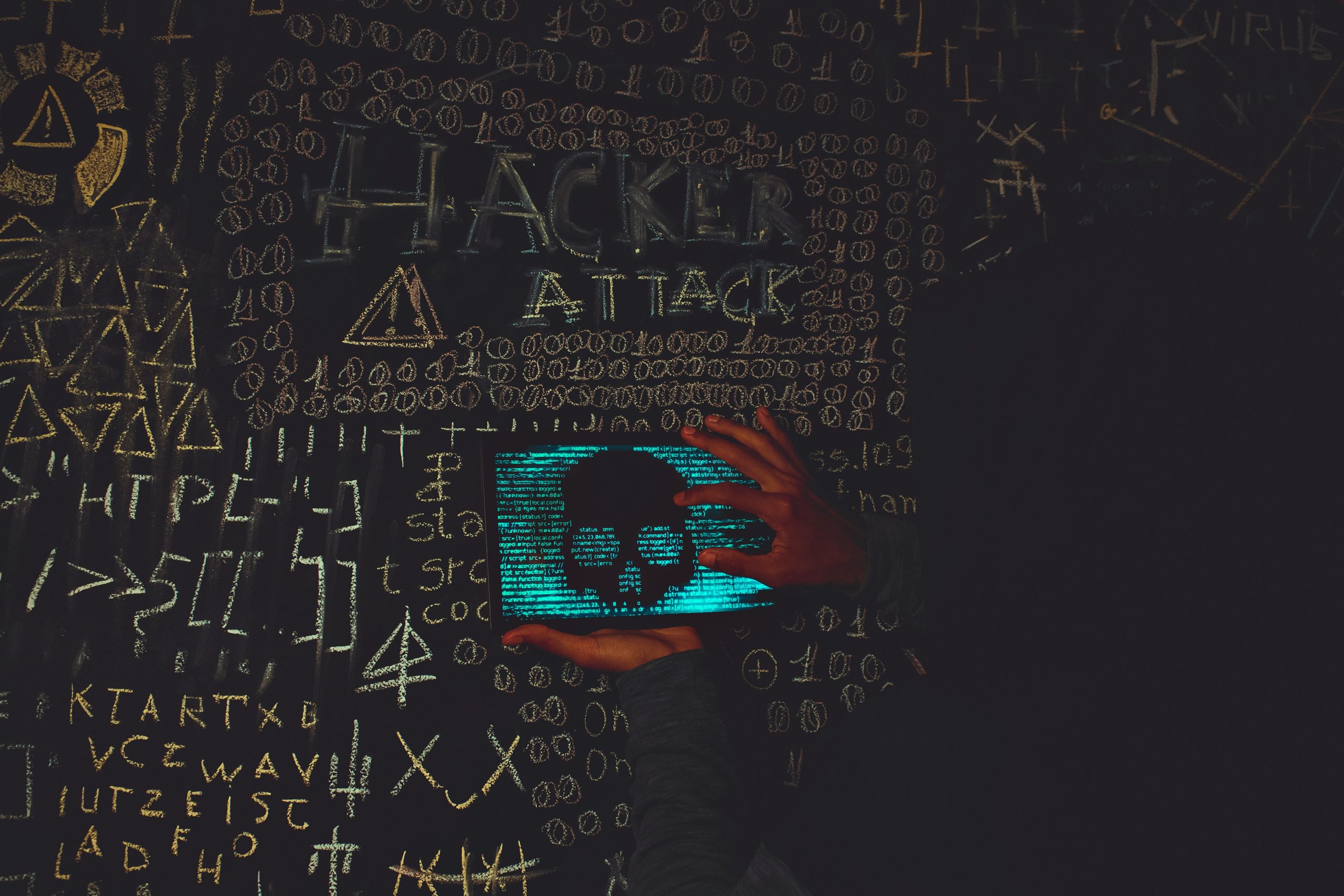 Hacker en capuche noire utilisant tablette avec symboles crâne