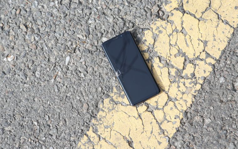 Smartphone fissuré posé sur le bitume