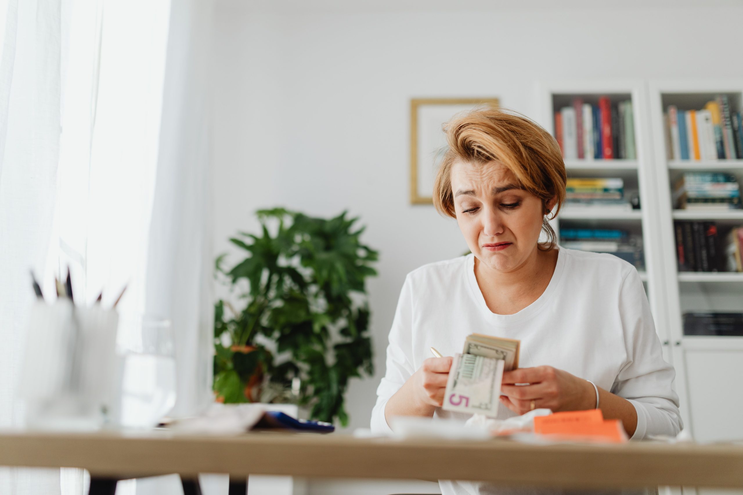 Femme inquiète comptant de l'argent à son bureau